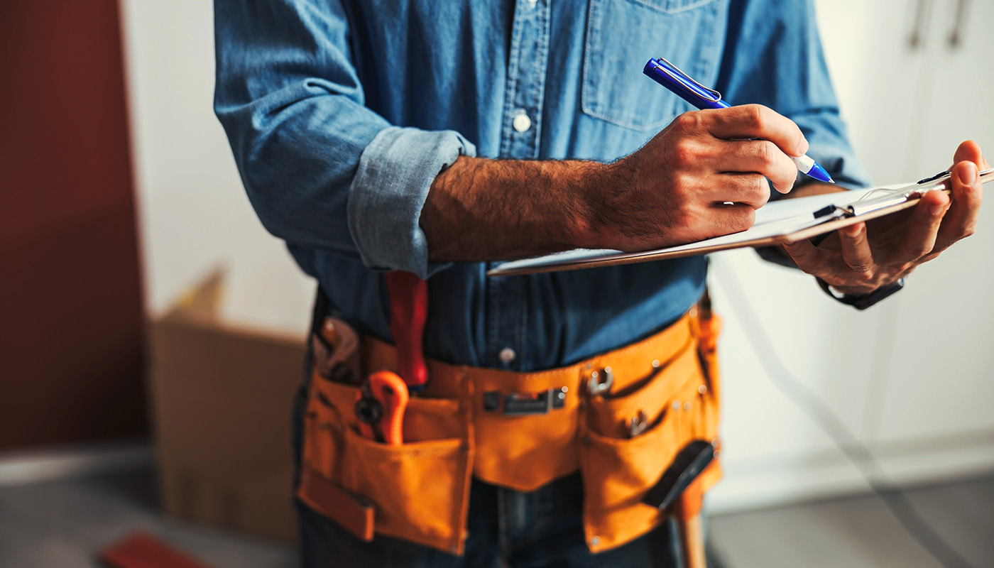A contractor making notes on a clipboard